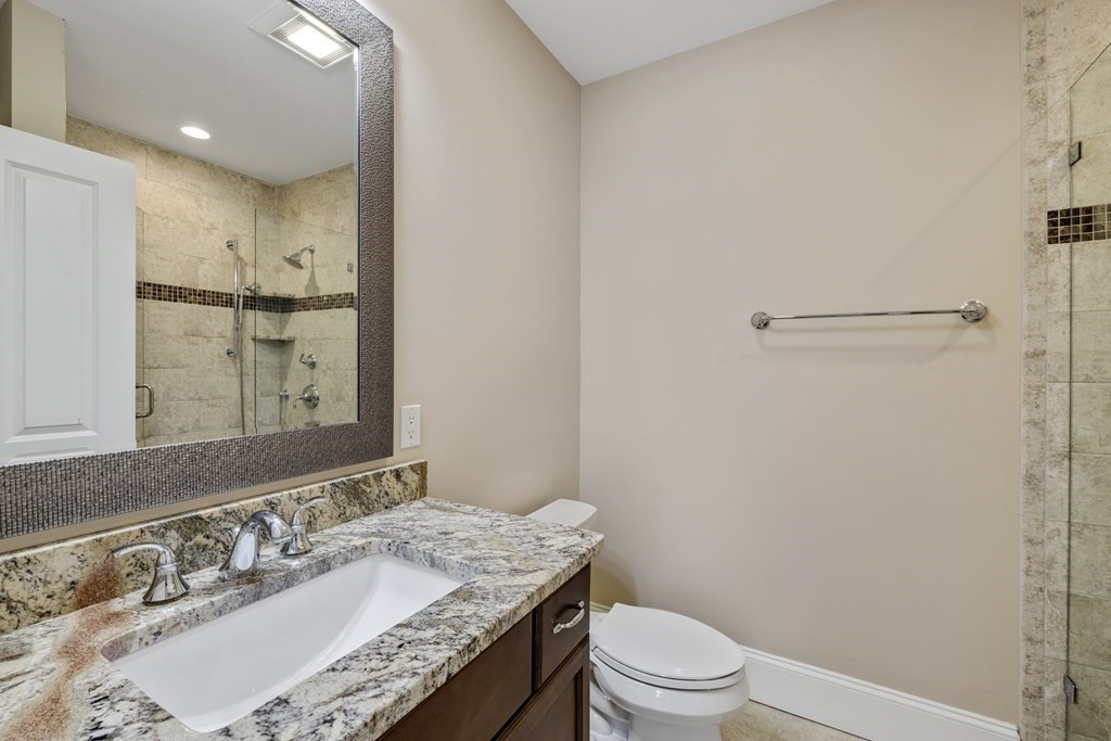 27 Webster Road Lexington, MA 02421 - Photo 36 of 42 a bathroom with a granite countertop sink a toilet a mirror and shower
