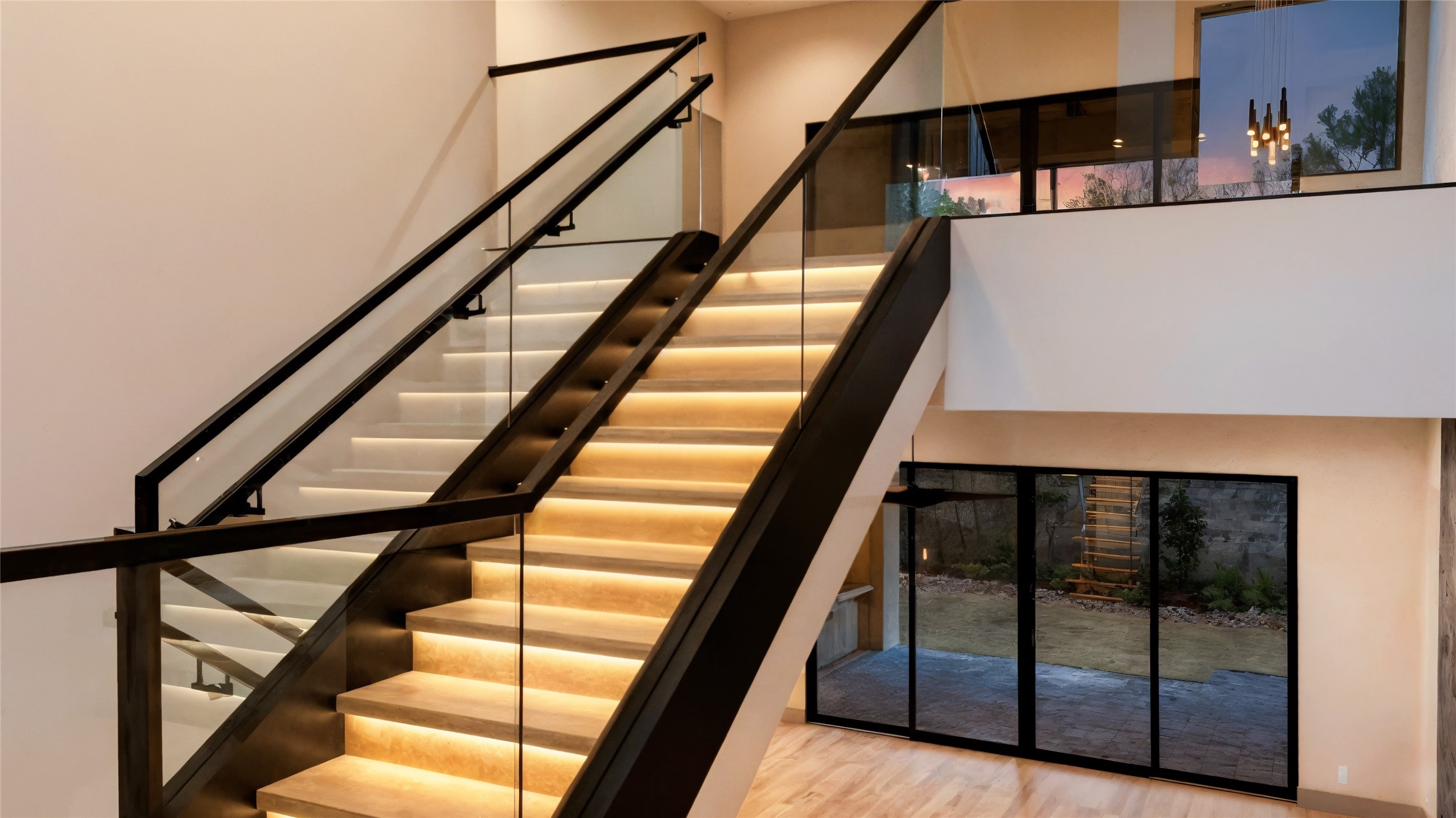47 Pronghorn Place Spring, TX 77389 - Photo 42 of 44 This home features a modern staircase with sleek glass railings and ambient lighting. The open floor plan includes large windows and a sliding glass door, providing plenty of natural light and easy access to the outdoor space.