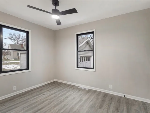 a view of an empty room with a window and wooden floor