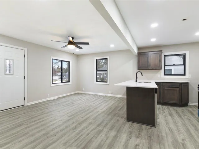 a view of a kitchen with a sink cabinet a ceiling fan and wooden floor