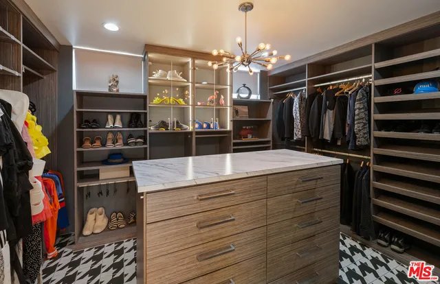 a view of walk in closet with clothes and shoes