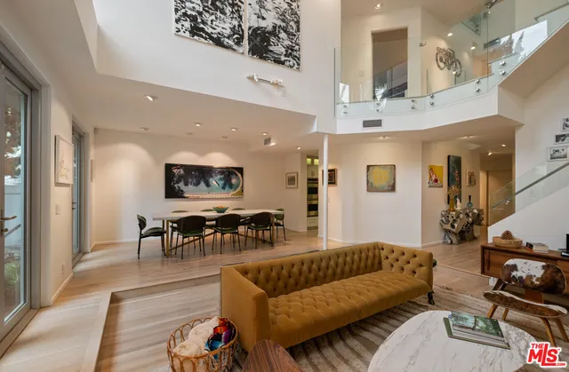 a living room with furniture kitchen view and a wooden floor
