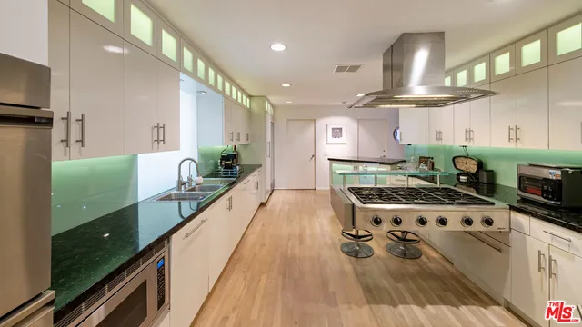 a kitchen with stainless steel appliances a stove a sink and a wooden floors