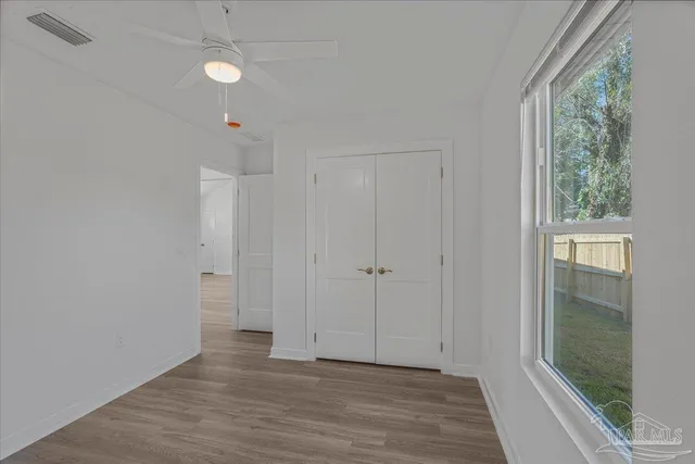 a view of hallway with window and wooden floor