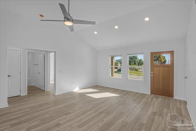 a view of an empty room with a window and wooden floor