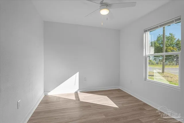 a view of an empty room with wooden floor and windows