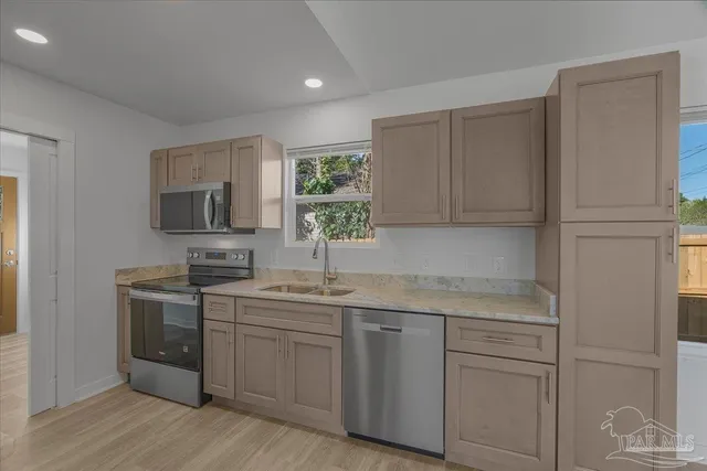 a kitchen with a sink dishwasher a refrigerator and a stove with wooden floor