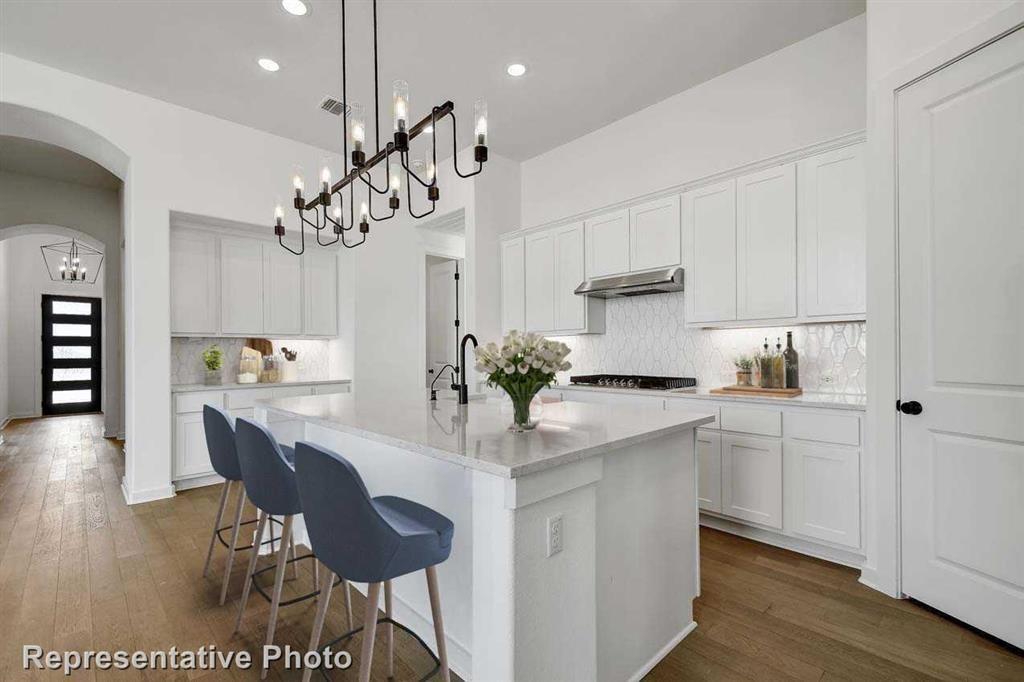 a kitchen with stainless steel appliances granite countertop a sink a stove a dining table and chairs