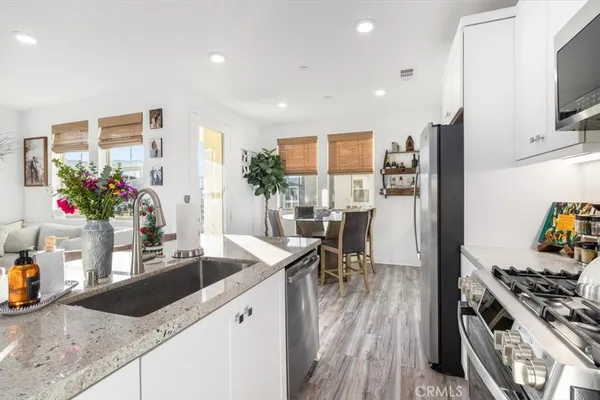 a kitchen with stainless steel appliances granite countertop a sink dishwasher a refrigerator and a stove with wooden floor