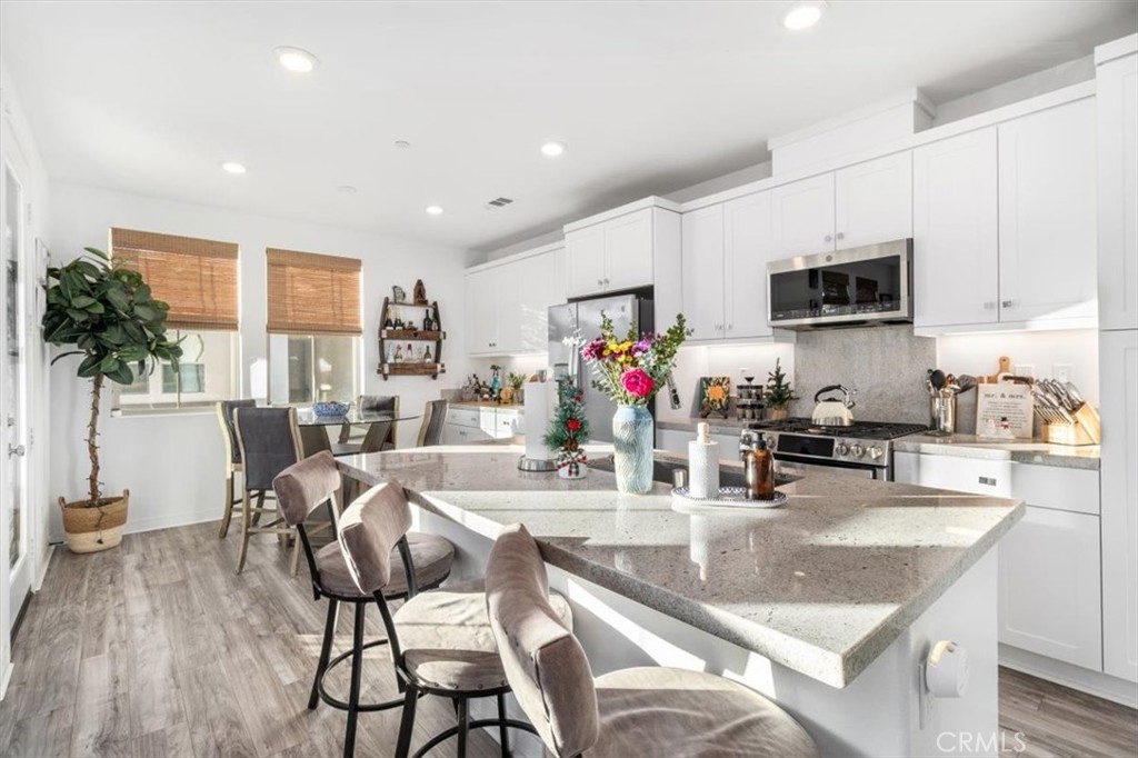 1201 Lasso Way Rancho Mission Viejo, CA 92694 - Photo 7 of 55 a kitchen with stainless steel appliances granite countertop a stove top oven a sink a dining table and chairs with wooden floor