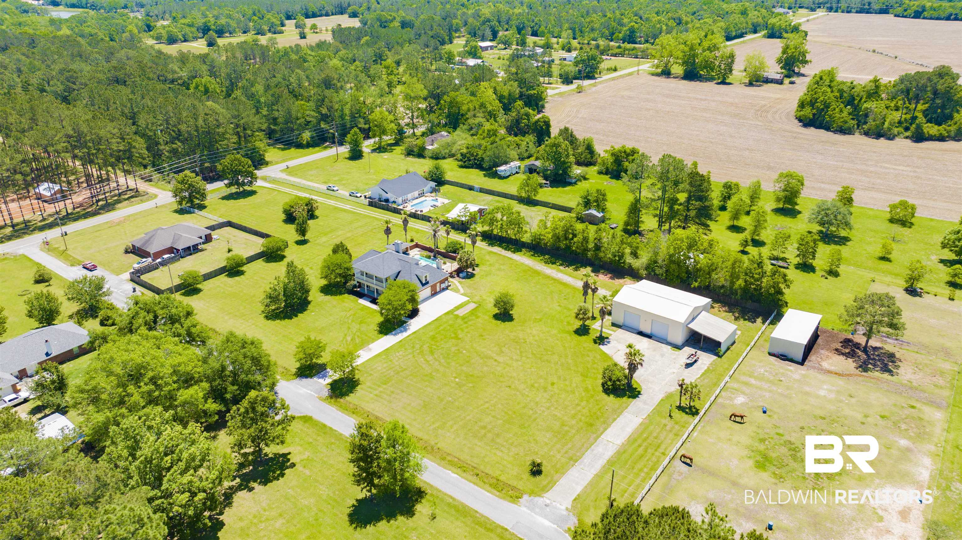 12944 Anna's Way Stapleton, AL 36578 - Photo 8 of 64 Expansive property featuring a large metal storage building, an additional smaller storage structure, and a fenced equestrian area