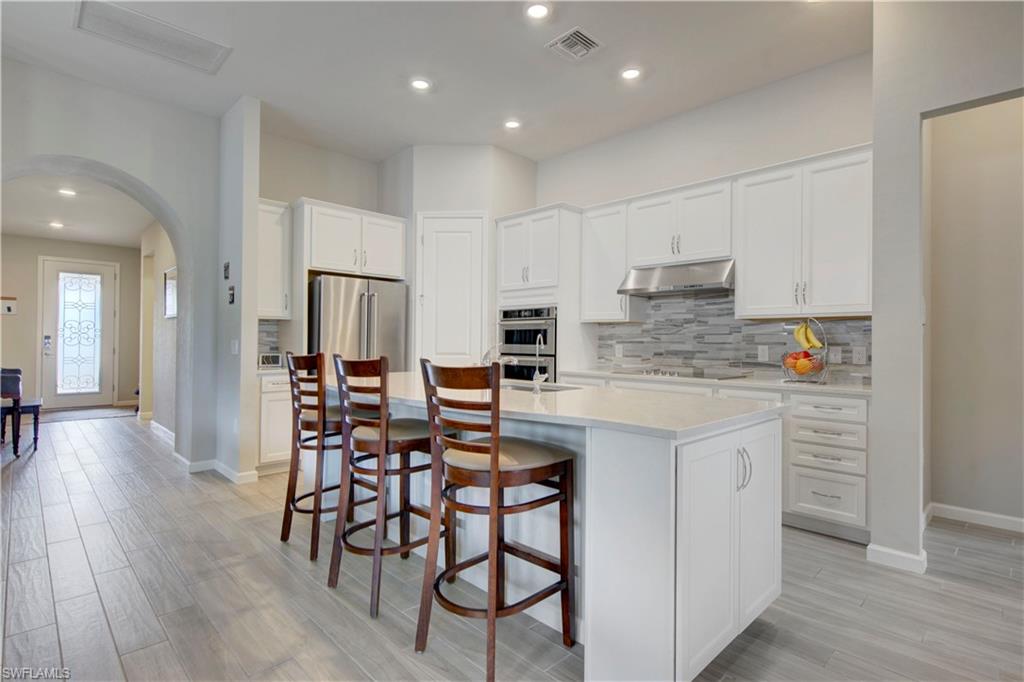 a kitchen with stainless steel appliances granite countertop a table chairs sink refrigerator and cabinets