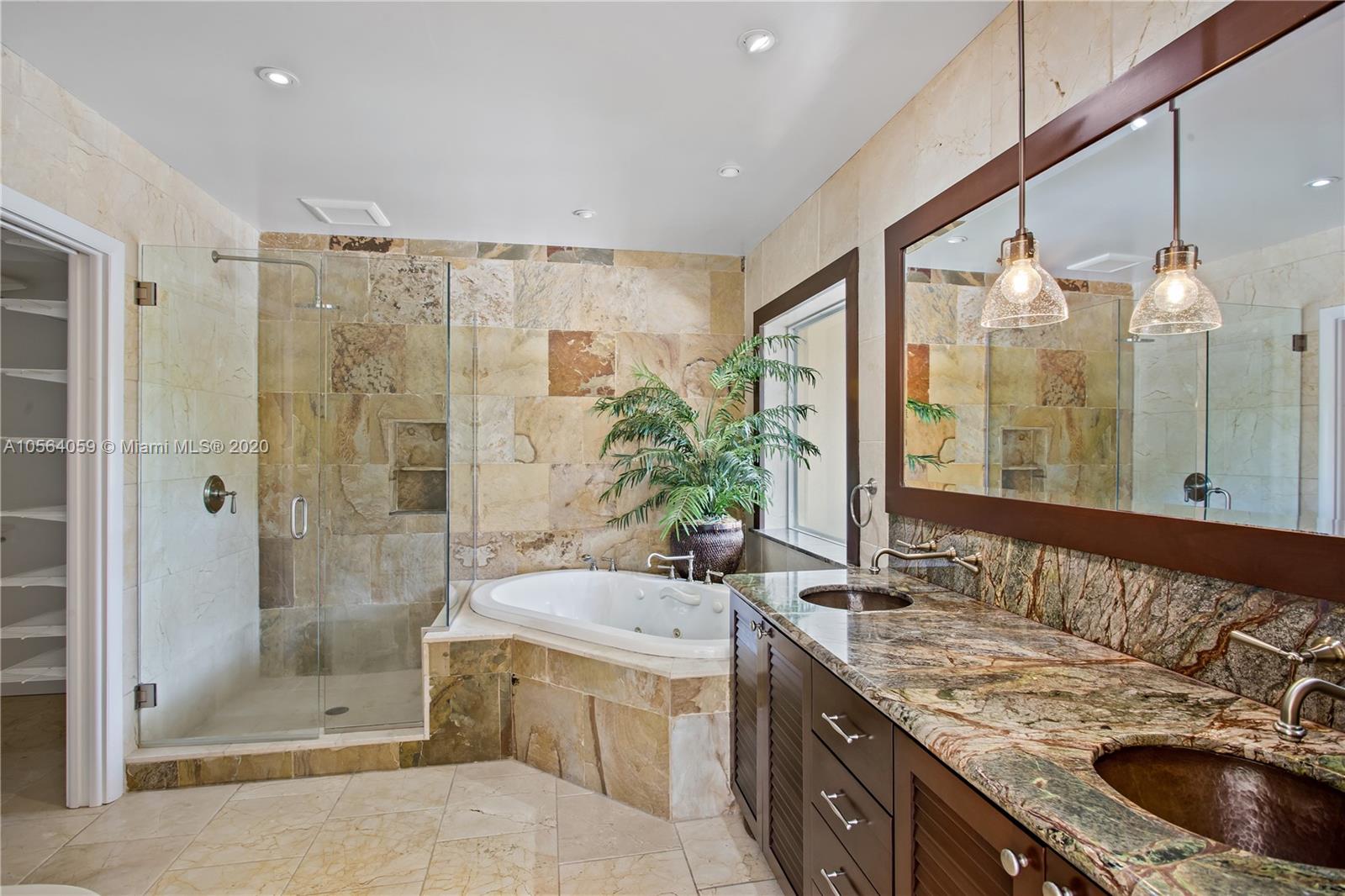 335 Pacific Road Key Biscayne, FL 33149 - Photo 21 of 50 a bathroom with a granite countertop tub a double vanity sink a mirror and a shower