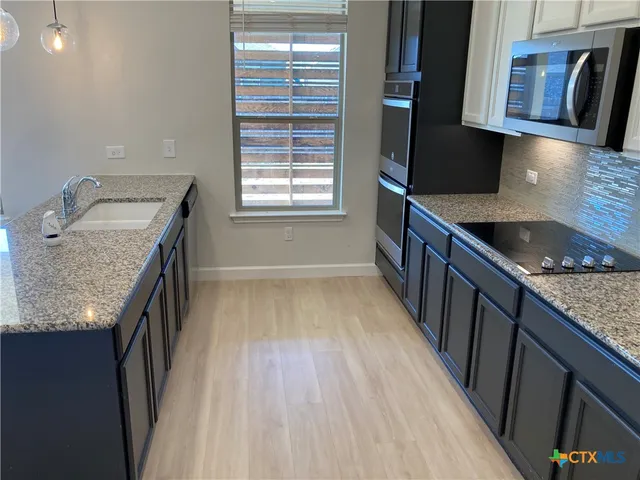 a kitchen with granite countertop a sink stove and cabinets