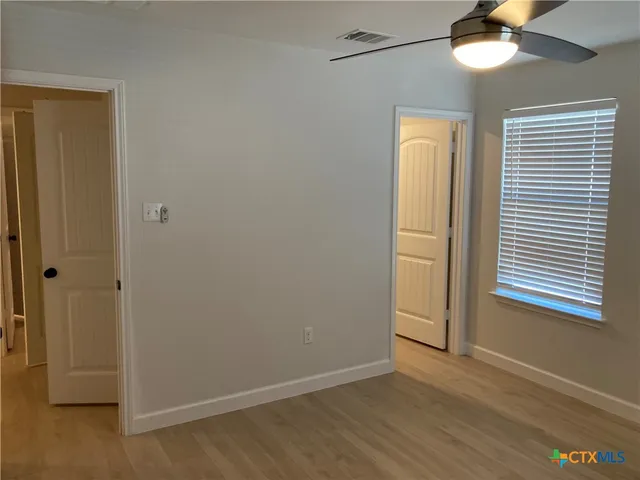 a view of an empty room with wooden floor and a window