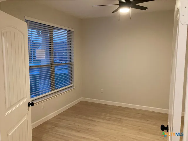 a view of an empty room with wooden floor and a window