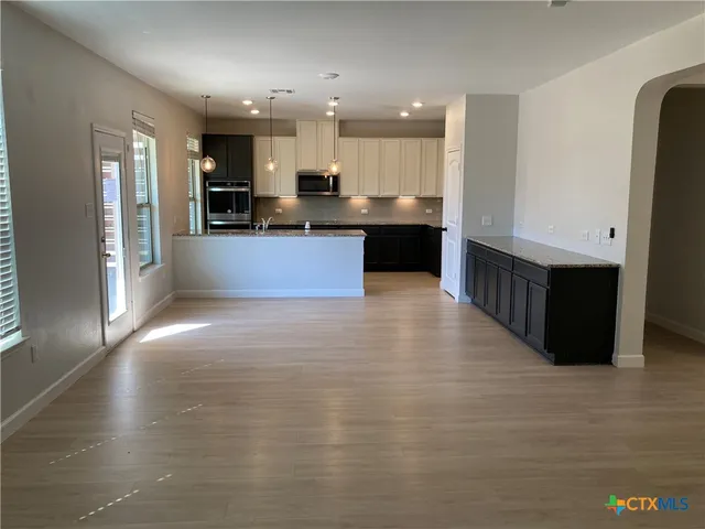 a large kitchen with stainless steel appliances kitchen island granite countertop a large counter top and a stove top oven