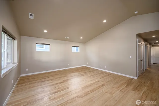 a view of an empty room with a window and wooden floor