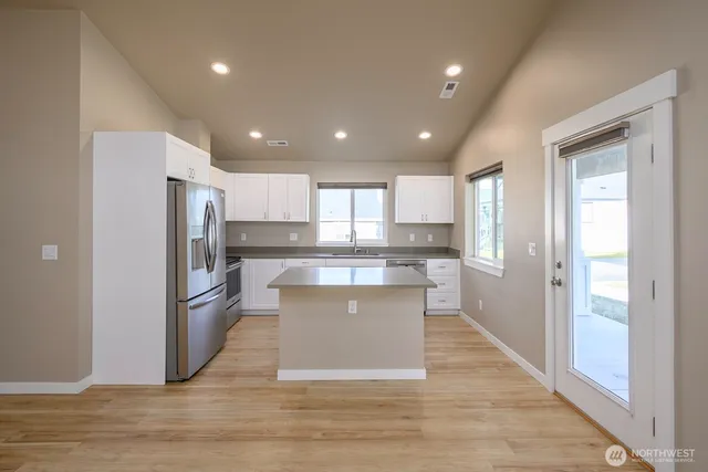 a kitchen with stainless steel appliances granite countertop a sink a stove a refrigerator and cabinets