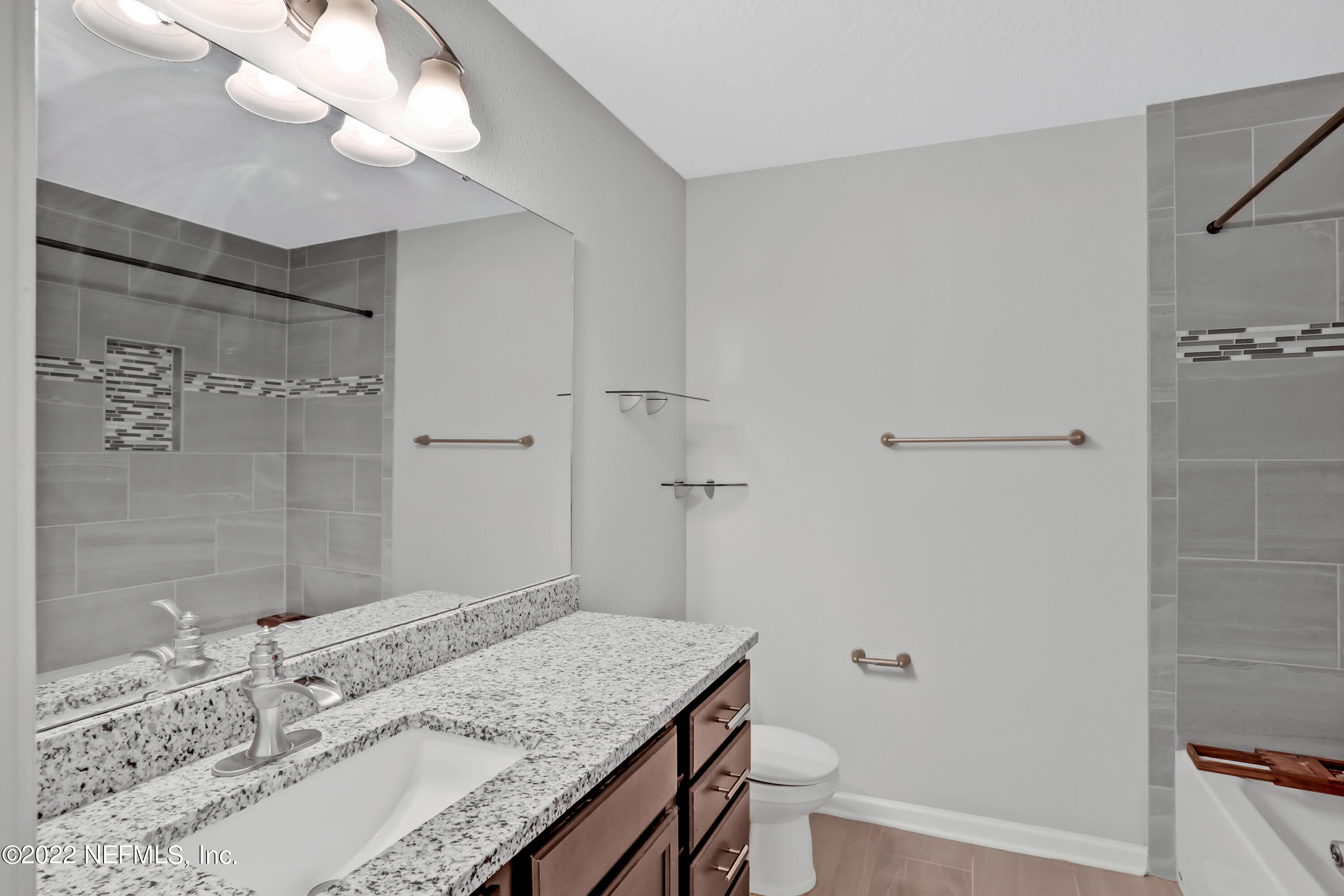 7507 Hilsdale Road Jacksonville, FL 32216 - Photo 27 of 38 a bathroom with a granite countertop sink a mirror and a shower