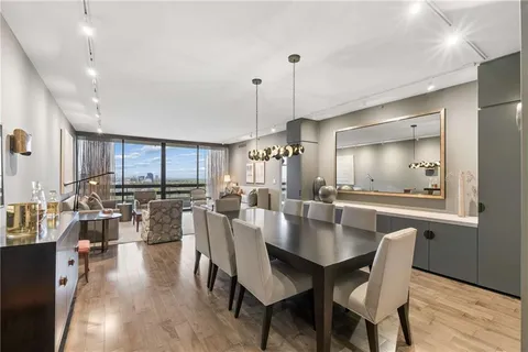a view of a dining room and livingroom with furniture wooden floor a rug a painting and a chandelier