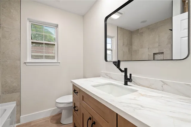 a bathroom with a granite countertop sink a toilet and a mirror