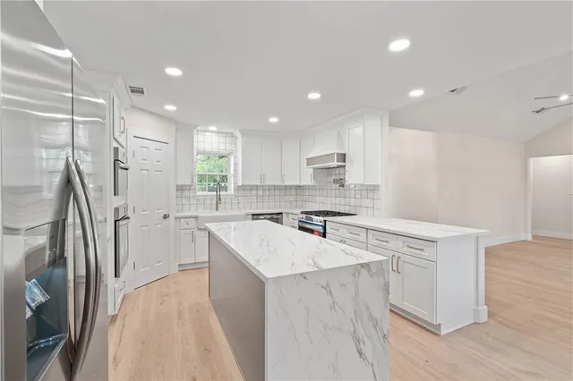 a kitchen with a sink a stove a refrigerator a center island and cabinets