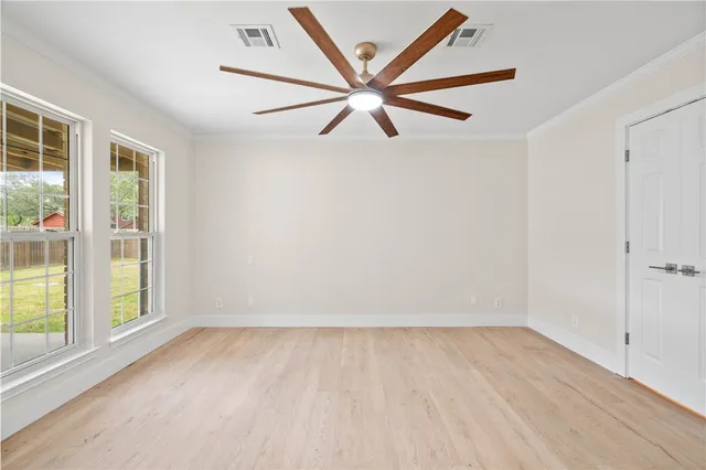 an empty room with wooden floor fan and windows