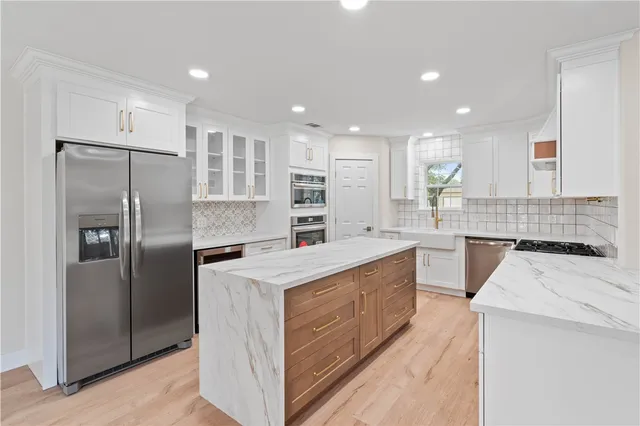 a kitchen with stainless steel appliances granite countertop a refrigerator a sink a stove and oven