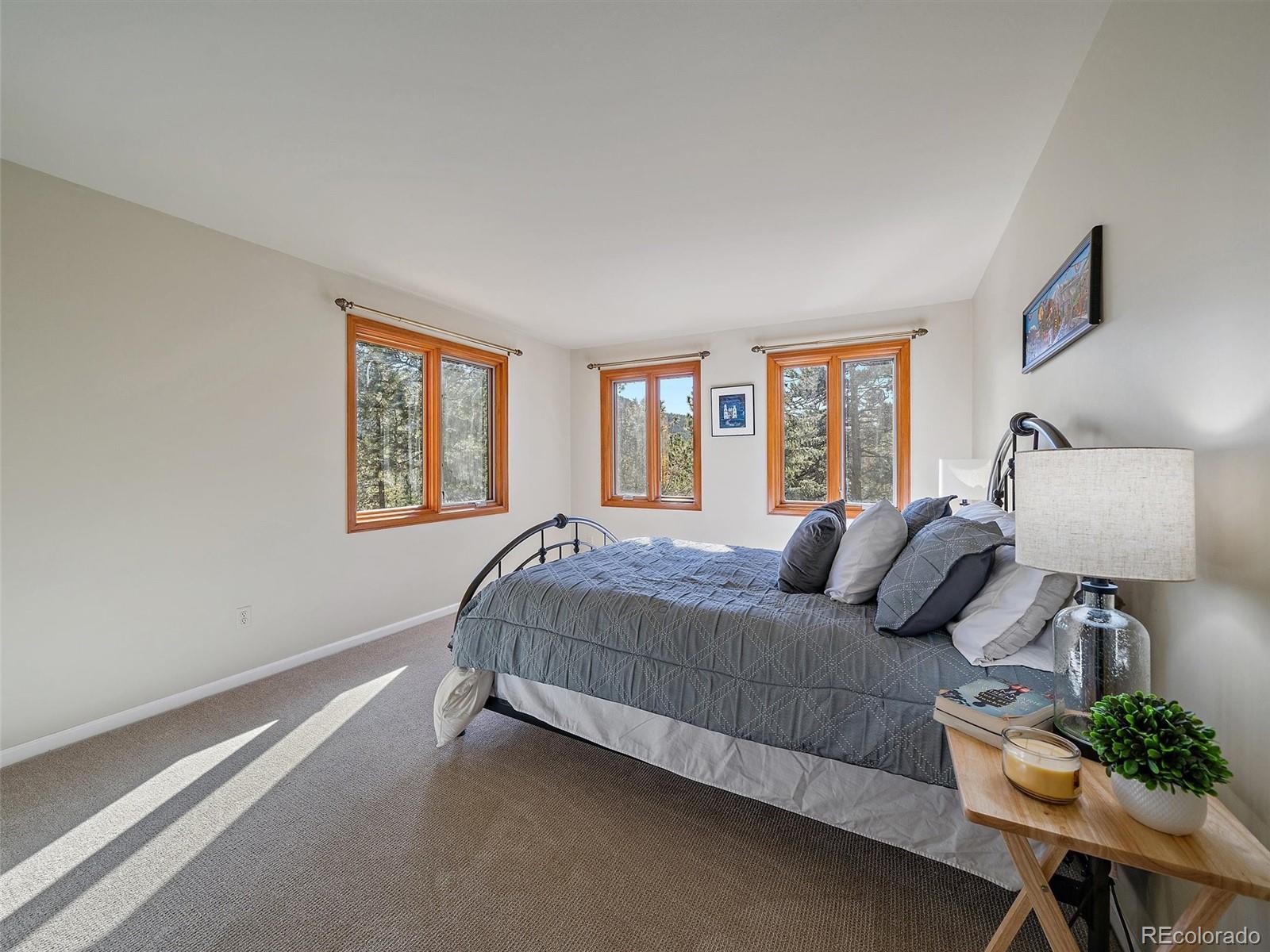 33913 Upper Bear Creek Road Evergreen, CO 80439 - Photo 26 of 45 a bedroom with a bed and a lamp