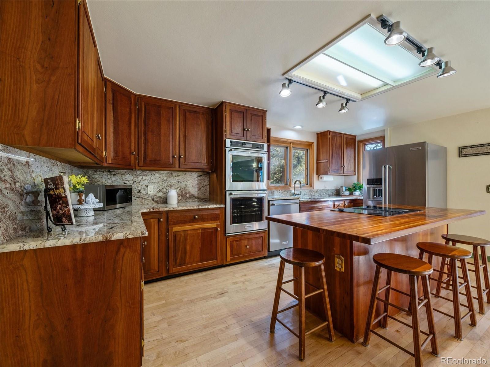 33913 Upper Bear Creek Road Evergreen, CO 80439 - Photo 4 of 45 a kitchen with stainless steel appliances granite countertop table chairs sink and cabinets