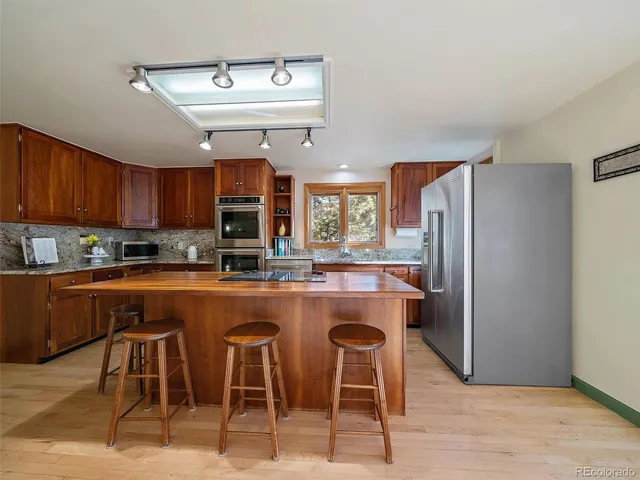 a kitchen with stainless steel appliances granite countertop a table chairs refrigerator and sink