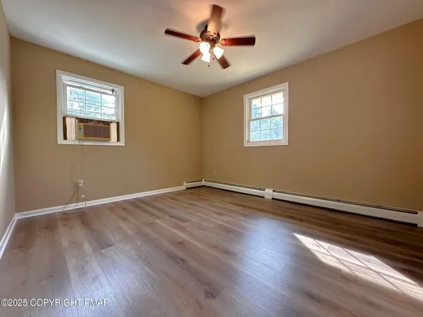 a view of an empty room with window and wooden floor