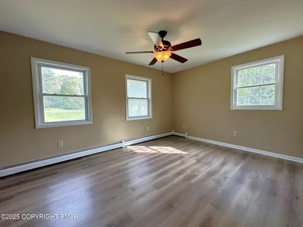 a view of empty room with wooden floor and fan