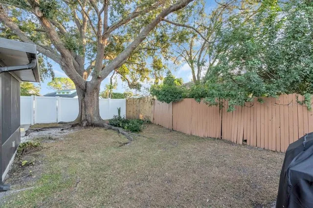 a backyard of a house with large trees and wooden fence