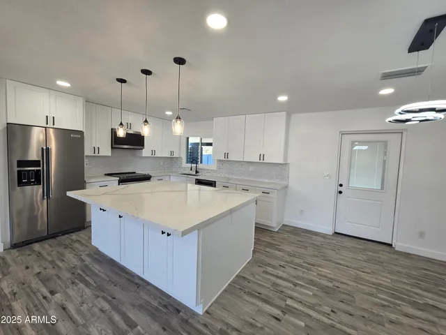 a large kitchen with kitchen island a sink stainless steel appliances and cabinets