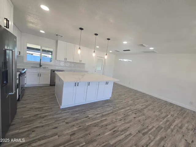 a large kitchen with stainless steel appliances granite countertop a large counter top a sink and a refrigerator