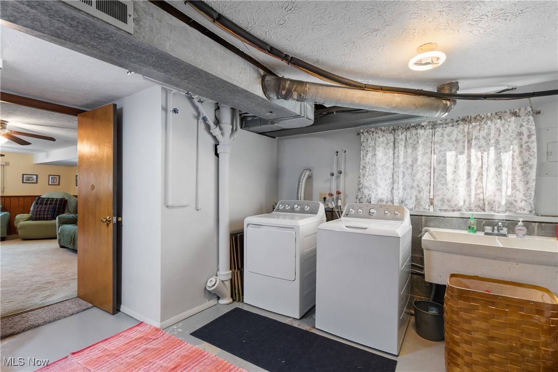 447 Center Road Bedford, OH 44146 - Photo 27 of 33 Laundry area with laundry area, a ceiling fan, washing machine and clothes dryer, a textured ceiling, and a sink