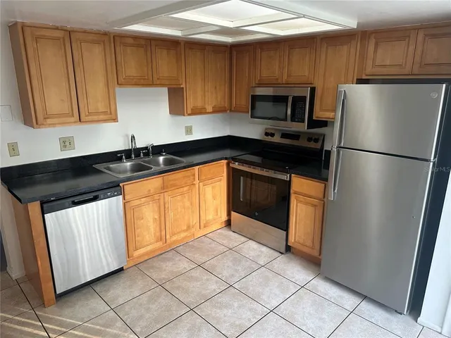 a kitchen with granite countertop a refrigerator a sink and a stove