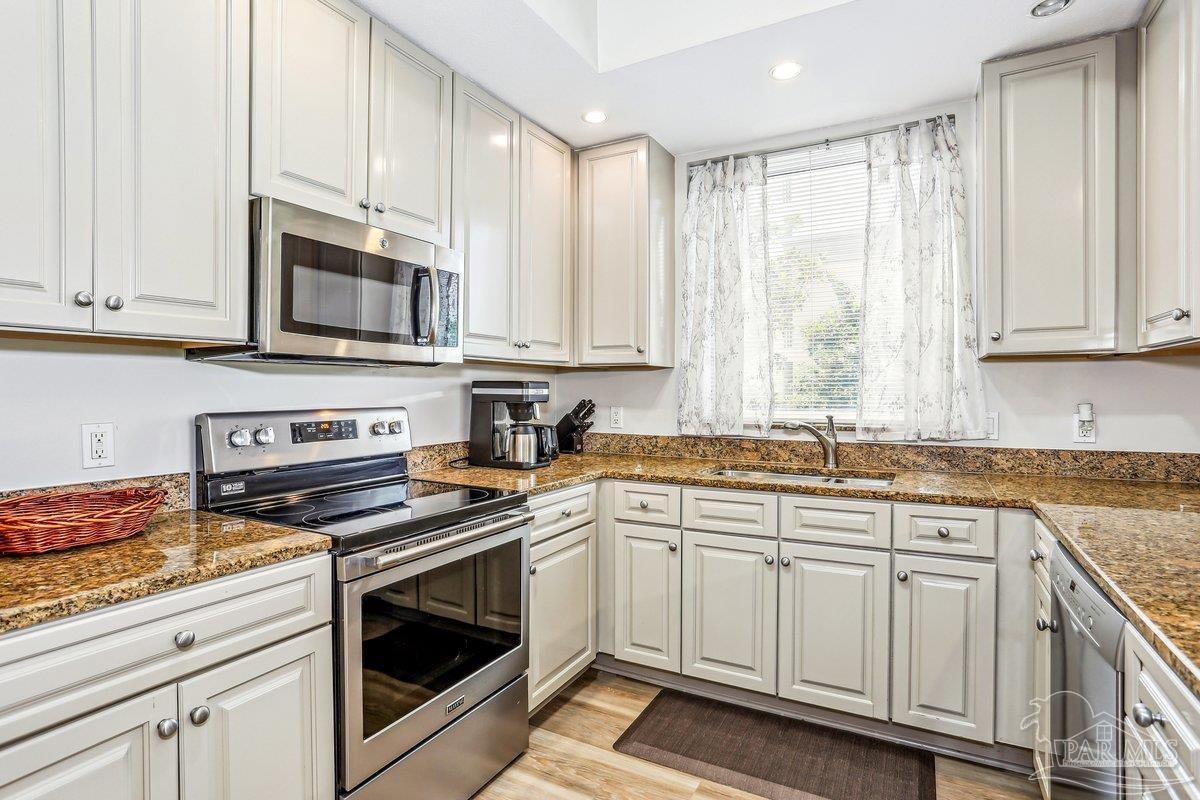 608 Lost Key Drive, Unit 201C Perdido Key, FL 32507 - Photo 10 of 42 a kitchen with granite countertop white cabinets and white appliances