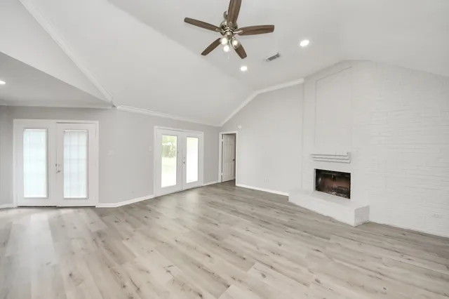 an empty room with wooden floor ceiling fan and windows