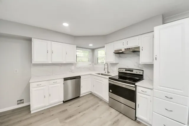 a kitchen with white cabinets and stainless steel appliances