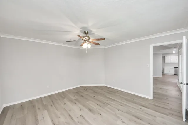 a view of a big room with wooden floor and chandelier fan