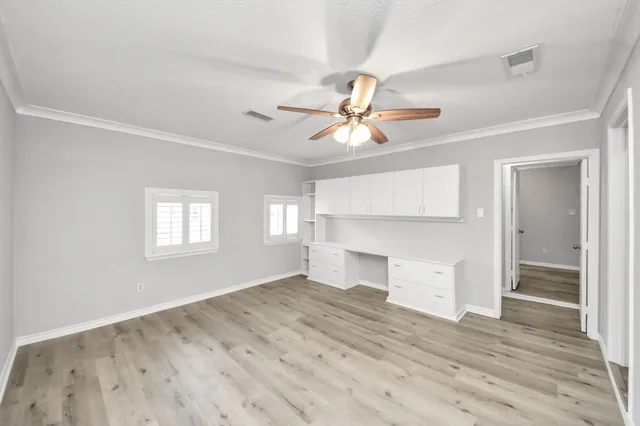 a view of empty room with wooden floor and fan