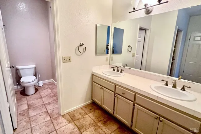 a bathroom with a double vanity sink toilet and a mirror