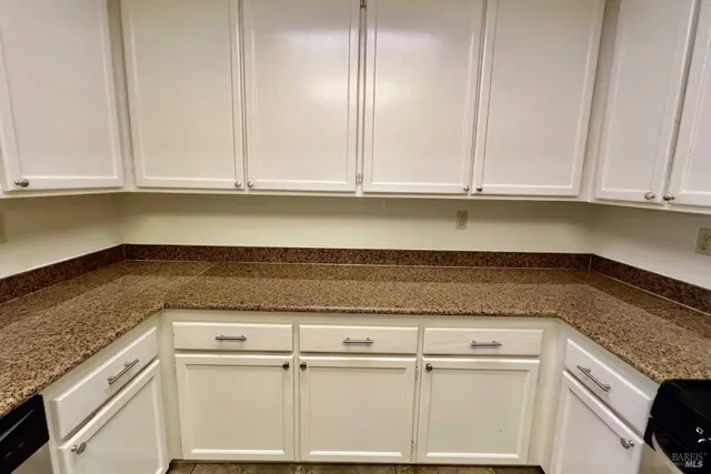 a kitchen with granite countertop white cabinets and a white stove top oven with granite countertops