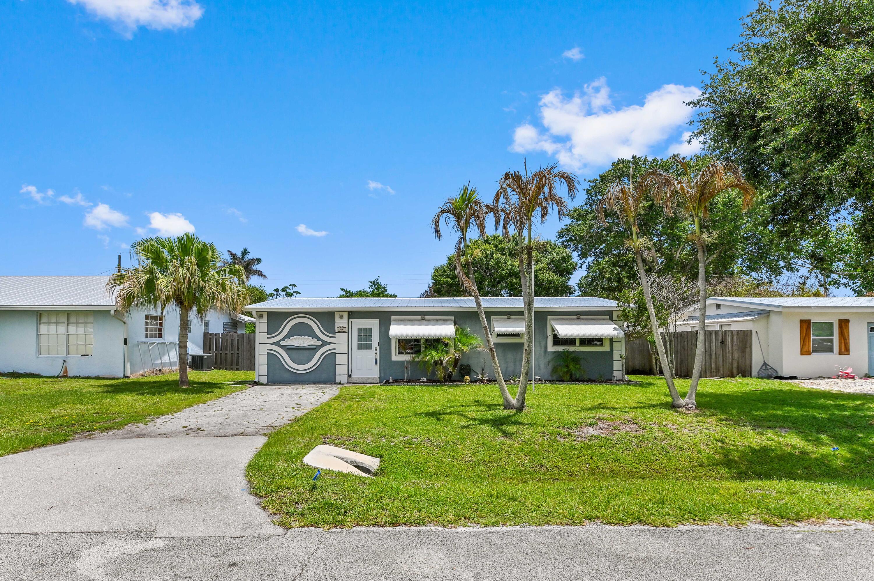 5709 Southeast Indigo Avenue Stuart, FL 34997 - Photo 1 of 26 a front view of a house with garden and trees