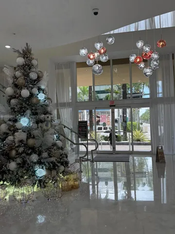 a view of a dining room with furniture a chandelier and large windows