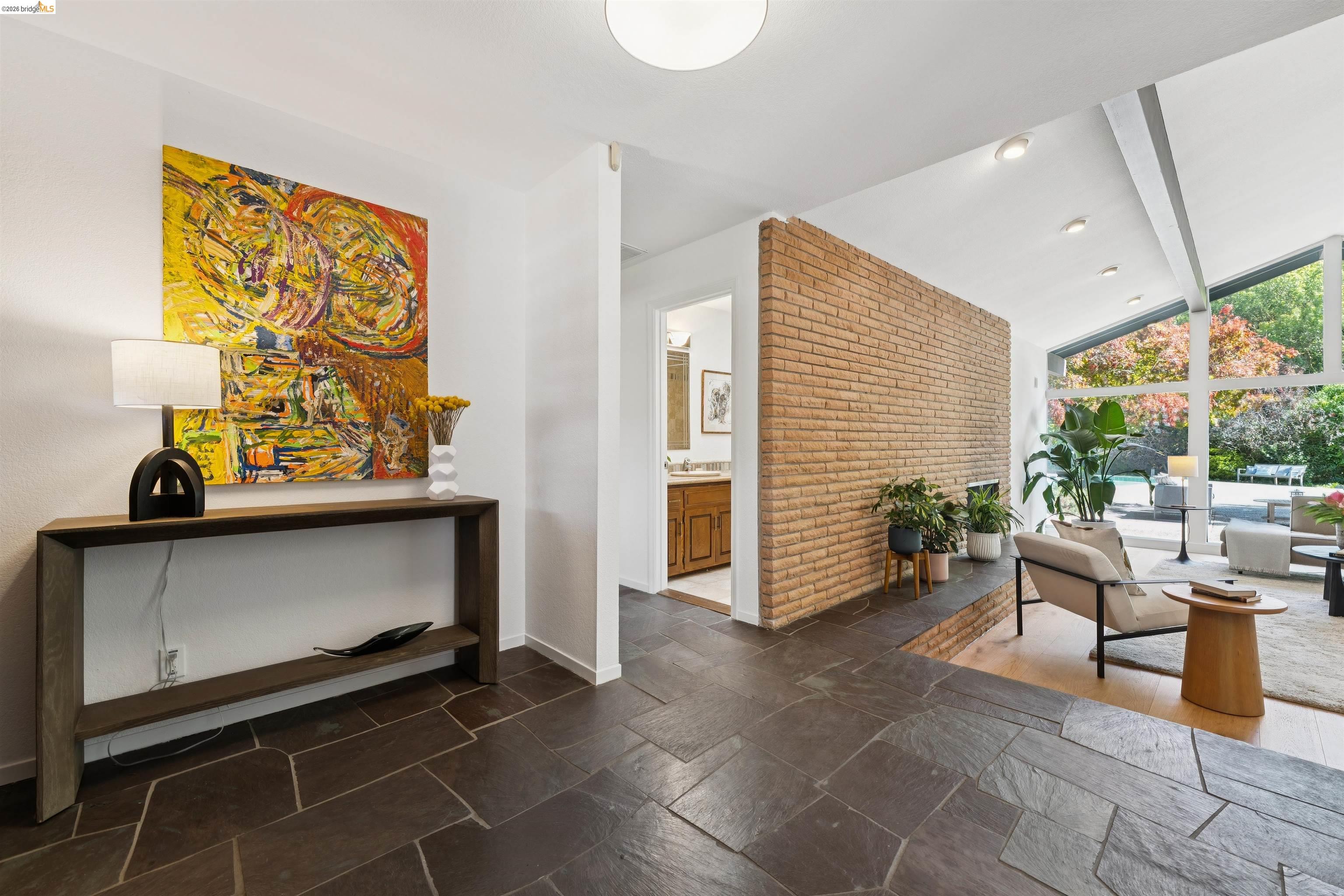 7 Jo Lin Court El Sobrante, CA 94803 - Photo 24 of 99 Slate tile flooring extending into a spacious living area with exposed brick accents, high vaulted ceilings, and extensive window walls