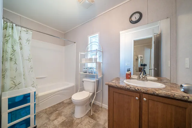 a bathroom with a granite countertop sink toilet a mirror and shower